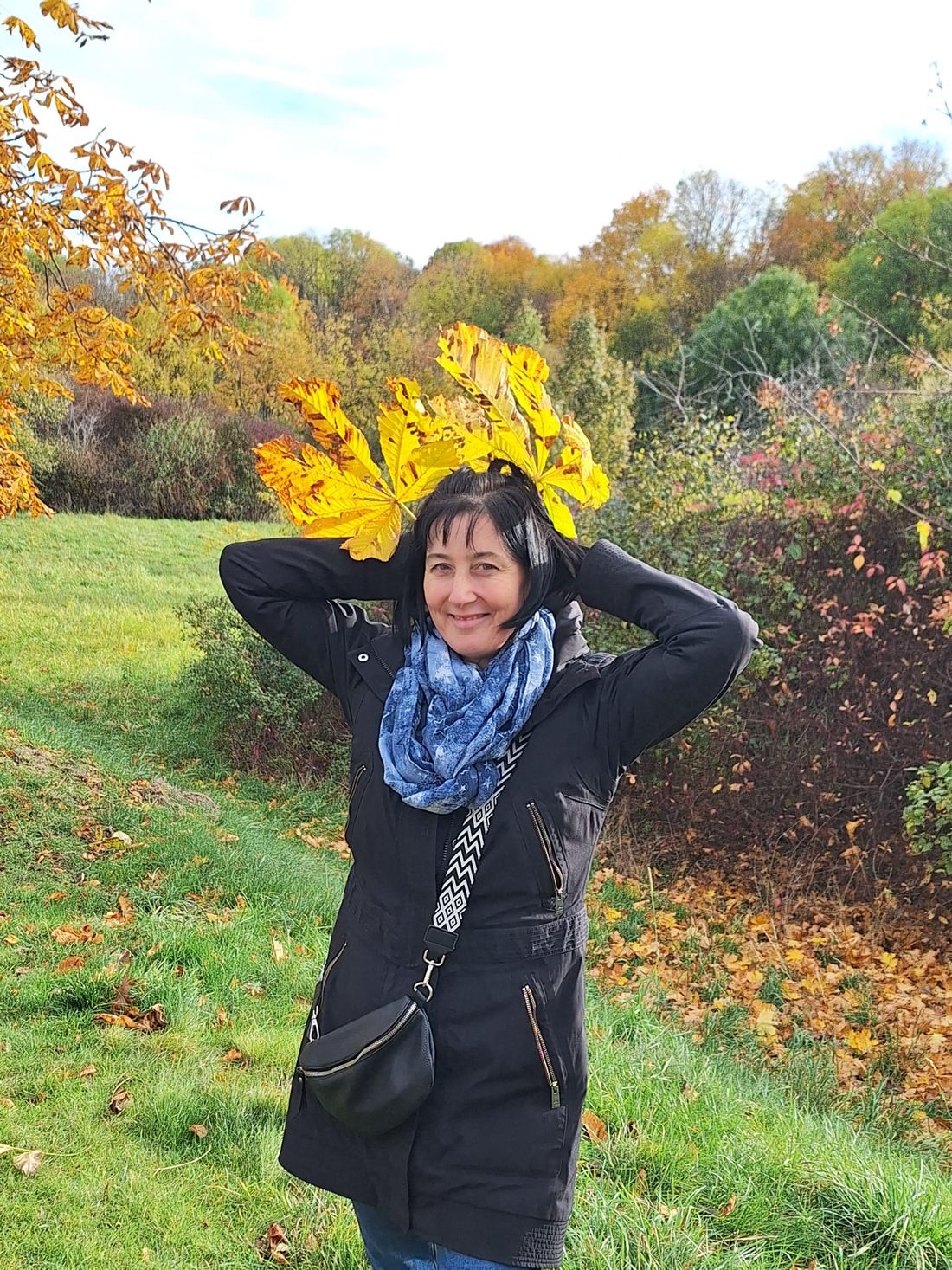 Katrin Starke lachend im Herbst, mit bunten Ahornblättern auf dem Kopf